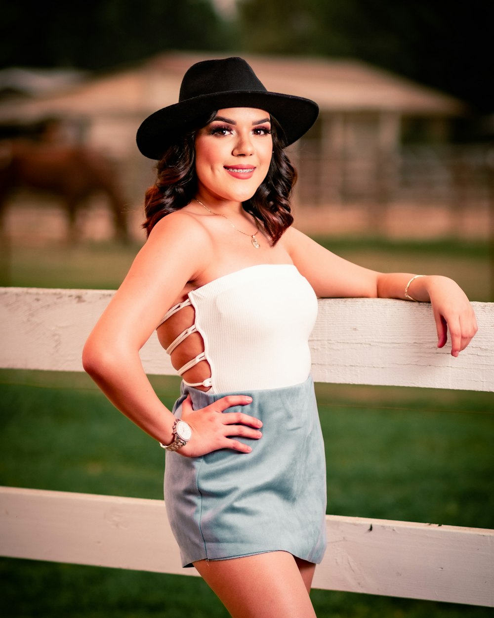 woman in white spaghetti strap top and blue denim jeans wearing black hat