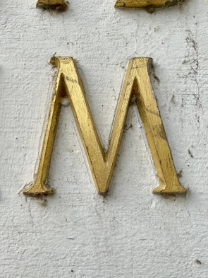 Close-up of a blue 3D printed letter 'M' showing detailed texture and glossy surface.