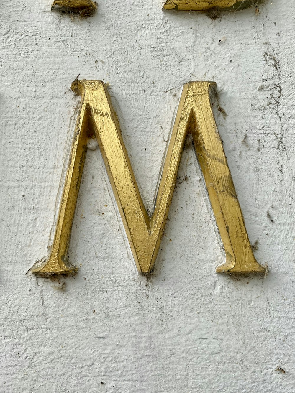 yellow wooden cross on white concrete wall