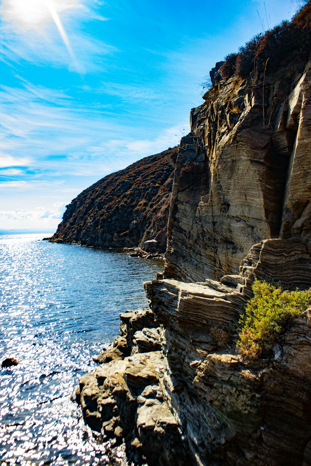 brown rocky mountain beside body of water during daytime