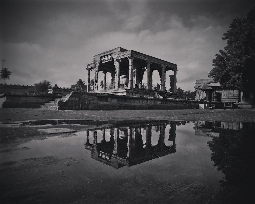 grayscale photo of concrete building near body of water