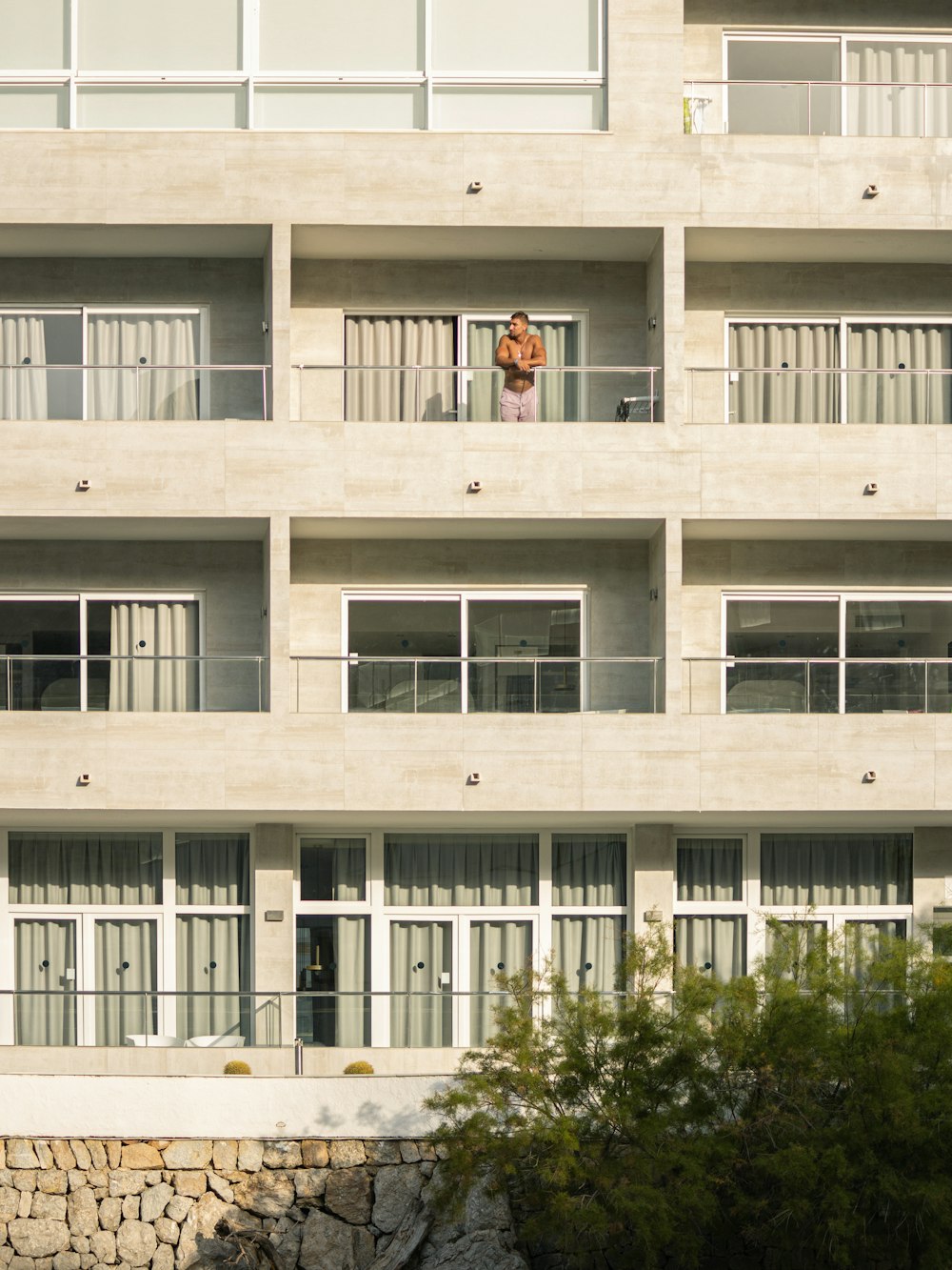 Edificio de hormigón blanco con árboles y plantas verdes