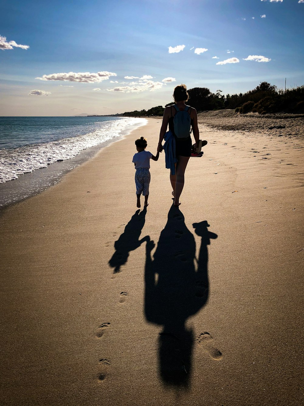 man in black jacket and black pants walking on beach during daytime