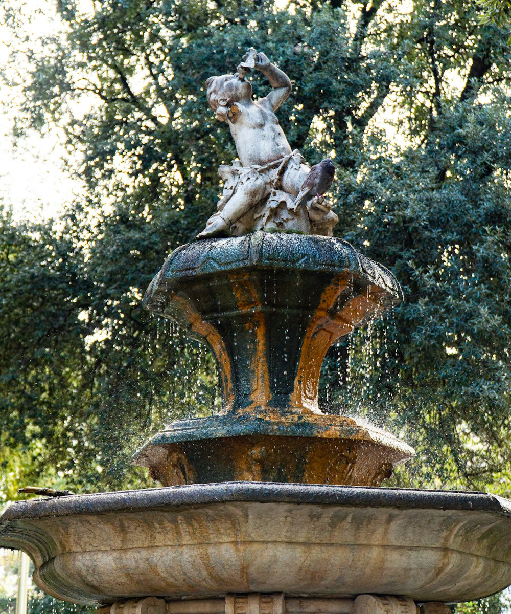 brown concrete fountain near green trees during daytime