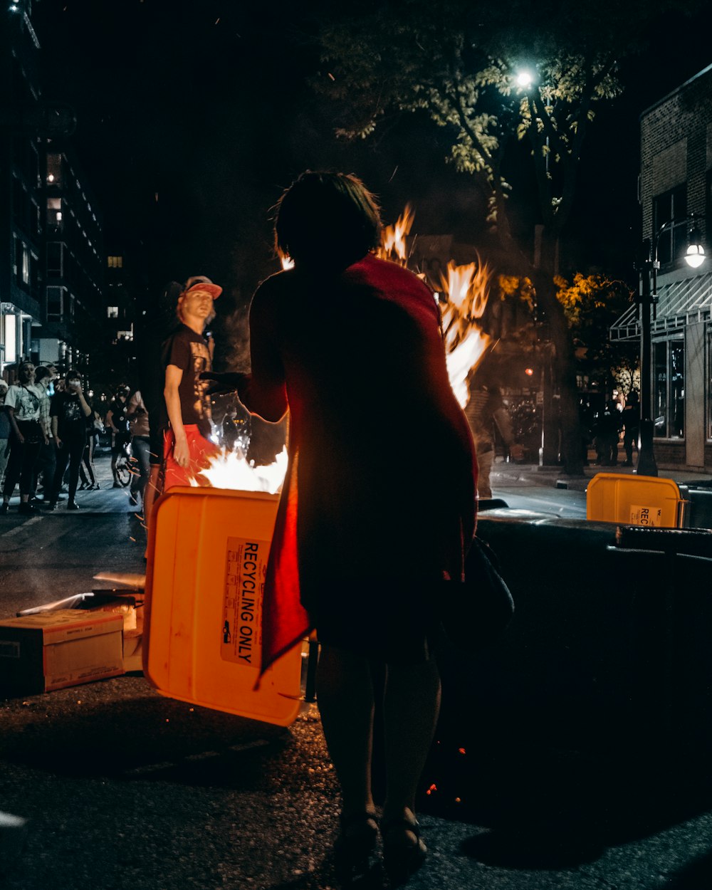 man in black shirt and pants standing beside red plastic crate during night time