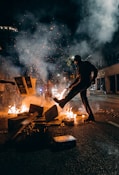 man in black t-shirt and black pants holding fire