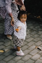girl in white shirt and black and white skirt holding brown wooden toy