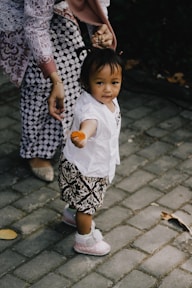 girl in white shirt and black and white skirt holding brown wooden toy
