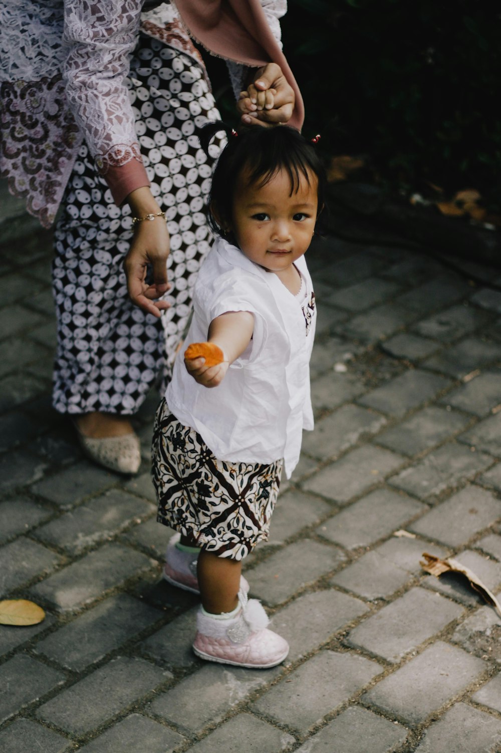 girl in white shirt and black and white skirt holding brown wooden toy