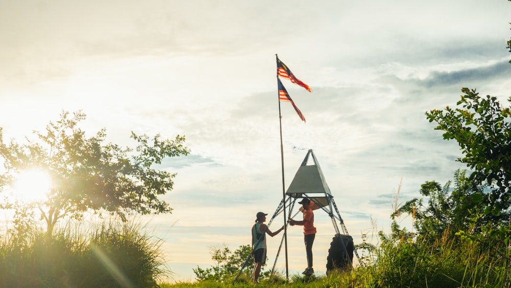 2 person standing on green grass field near flag of us a during daytime