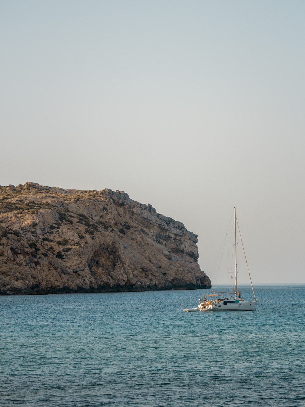 white boat on sea near brown rock formation during daytime