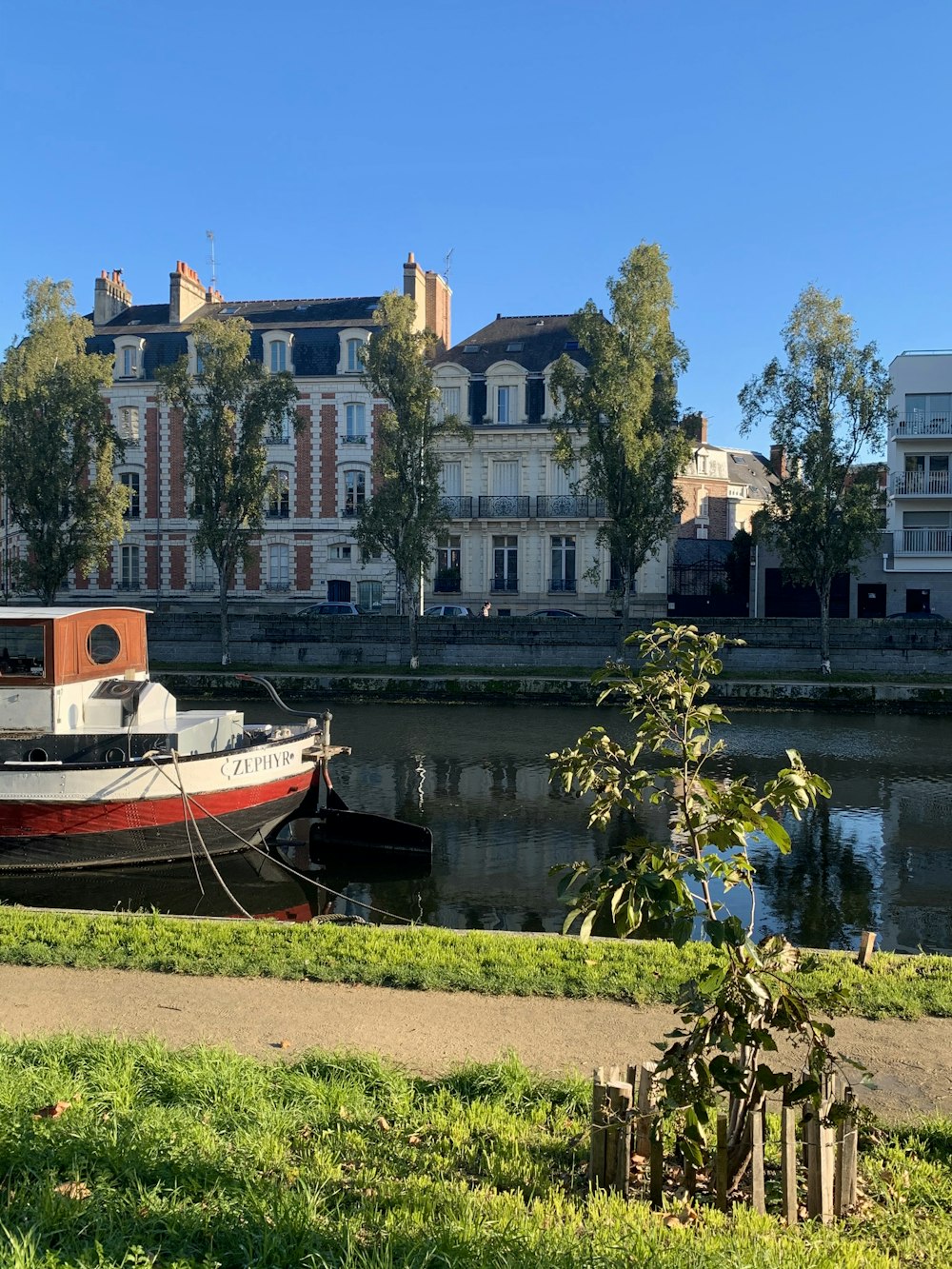 rot-weißes Boot tagsüber auf dem Wasser in der Nähe von Gebäuden