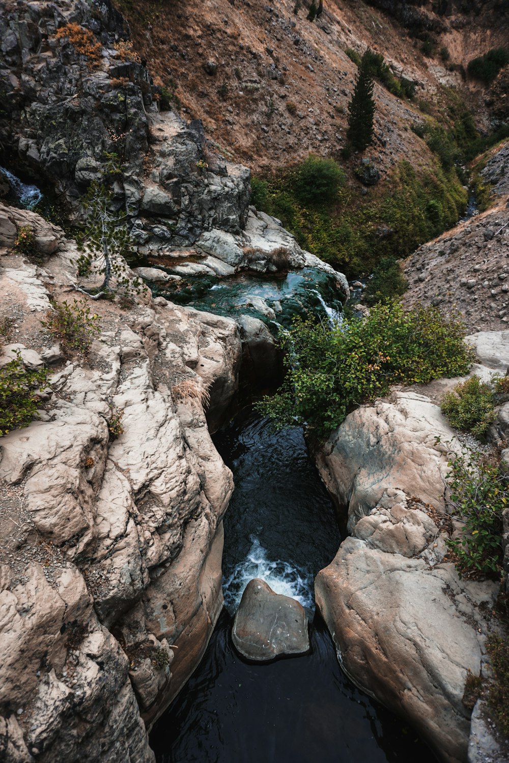 river in between rocky mountain during daytime