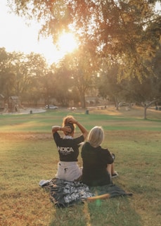 man in black t-shirt sitting on grass field during daytime