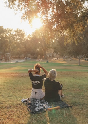 man in black t-shirt sitting on grass field during daytime