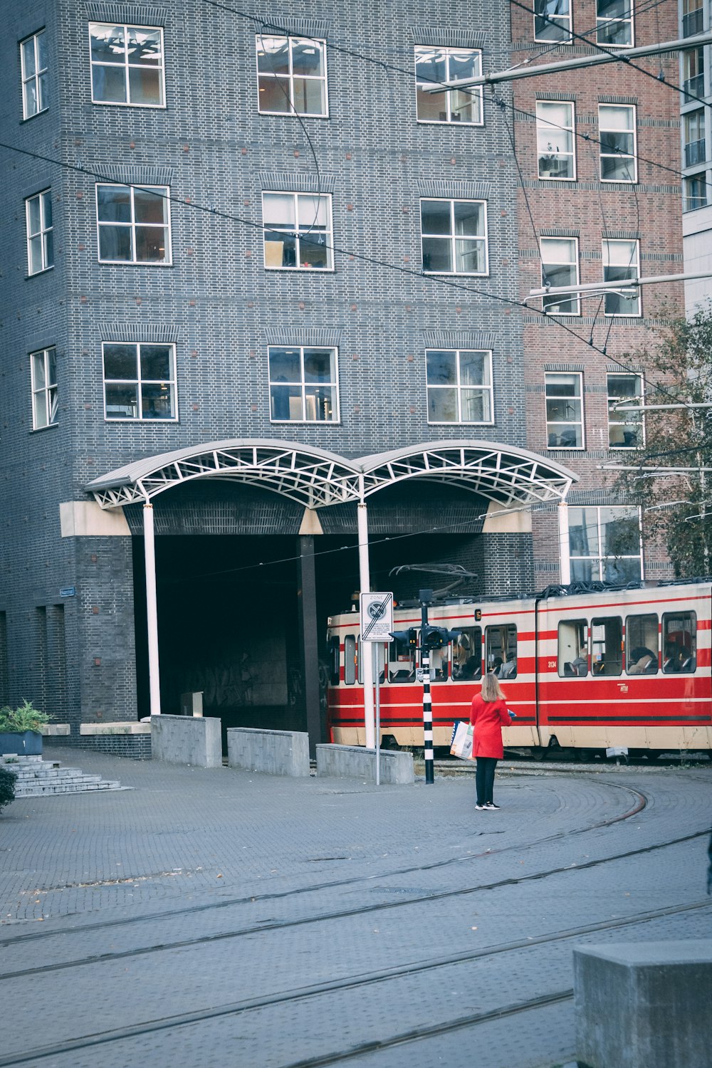 people in red and white train in front of brown and white concrete building during daytime