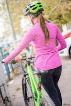 woman in pink long sleeve shirt and black pants riding green bicycle during daytime