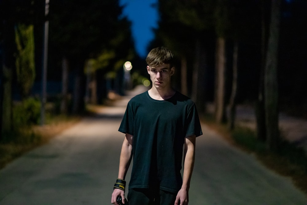 boy in blue crew neck t-shirt standing on road during daytime