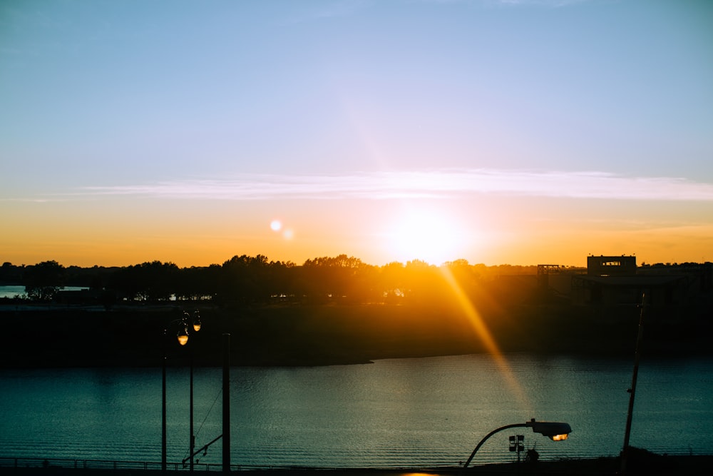 silhueta da bicicleta de montanha perto do corpo de água durante o pôr do sol