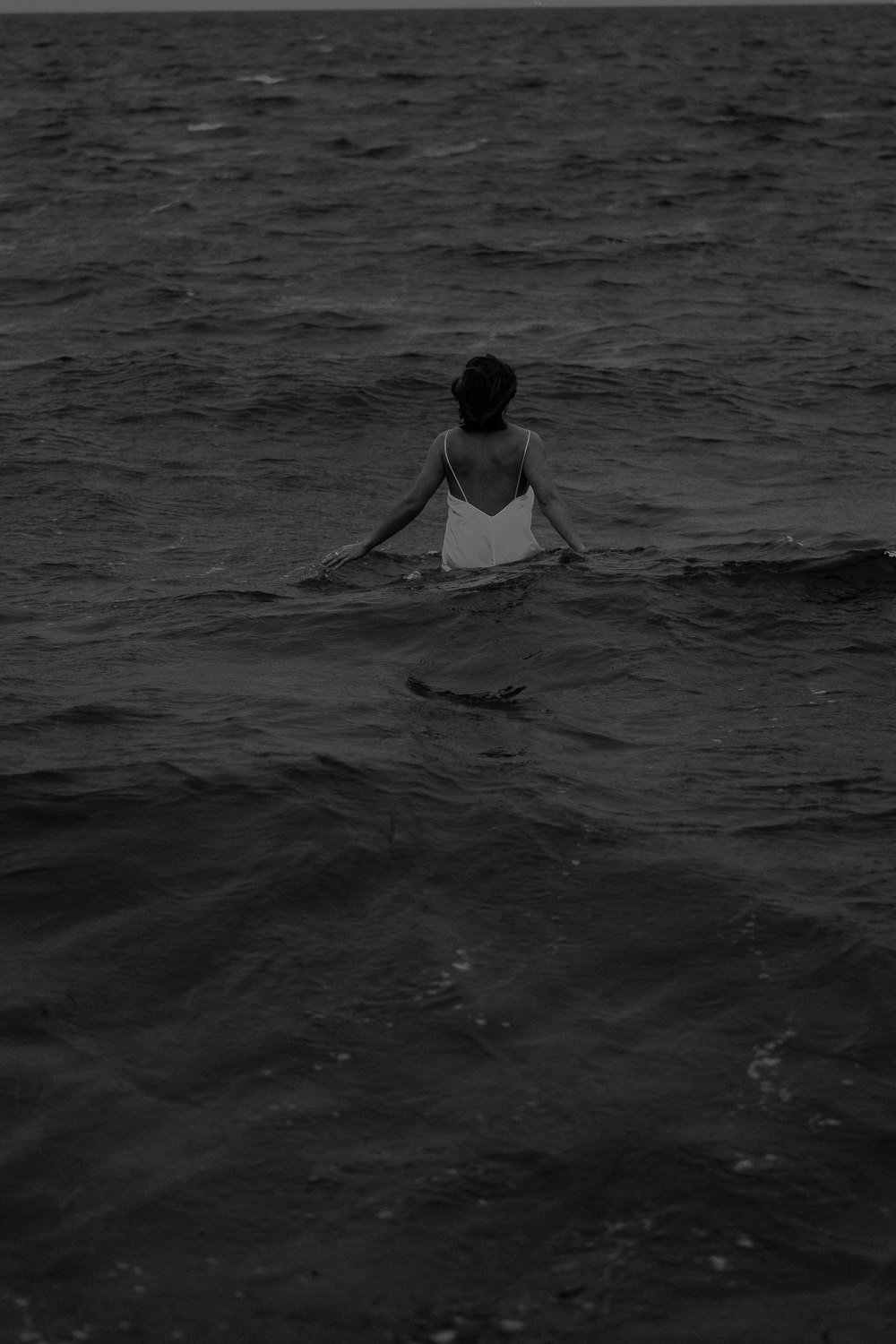 Photo en niveaux de gris d’un homme surfant sur la mer