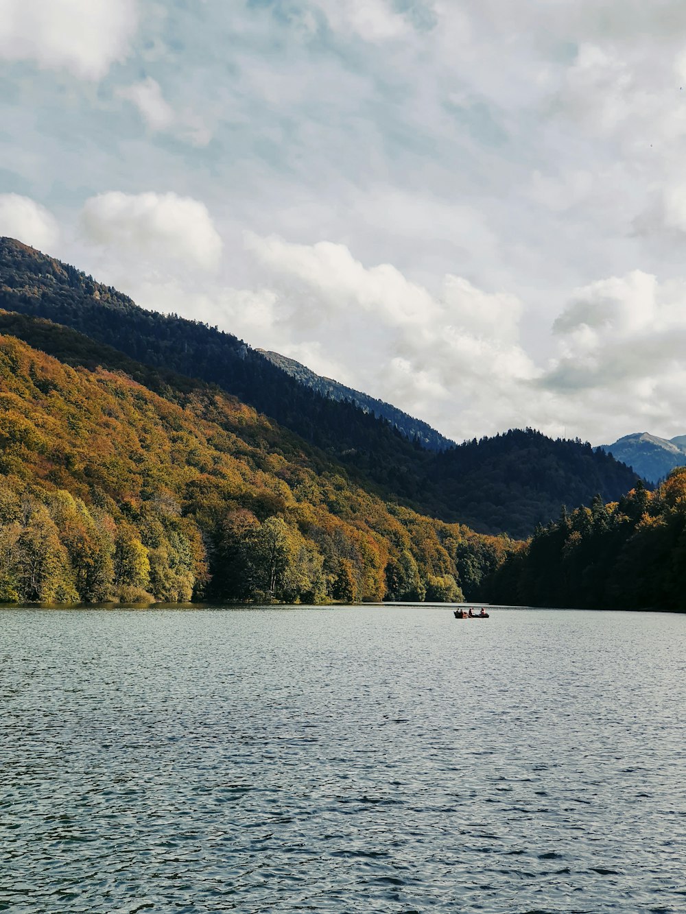 green and brown mountain beside body of water under cloudy sky during daytime