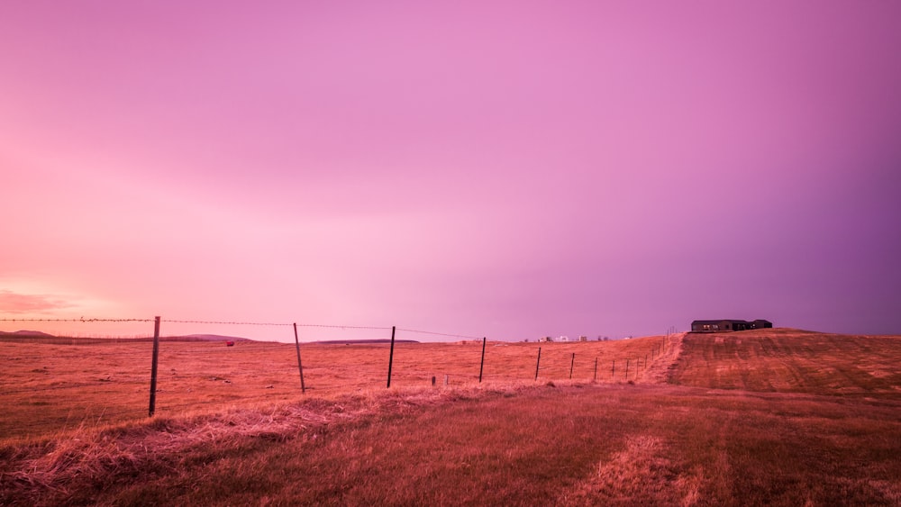 brown wooden fence on brown grass field under gray sky