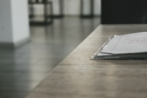 Stack of printed marketing copy drafts with red pen corrections on a wooden desk