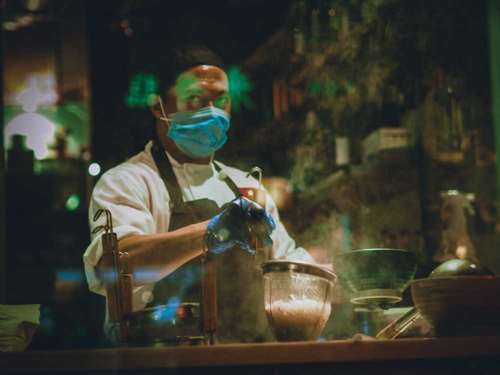 man in white shirt pouring water on clear drinking glass