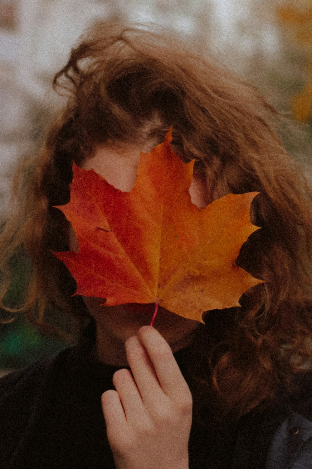 woman holding orange maple leaf