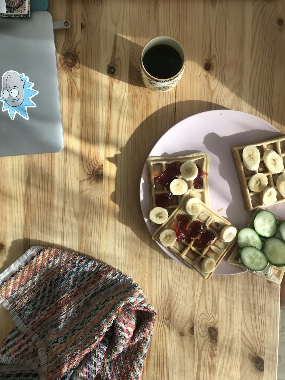 Frutas en rodajas en un plato de cerámica blanca junto a una taza de cerámica negra sobre una mesa de madera marrón