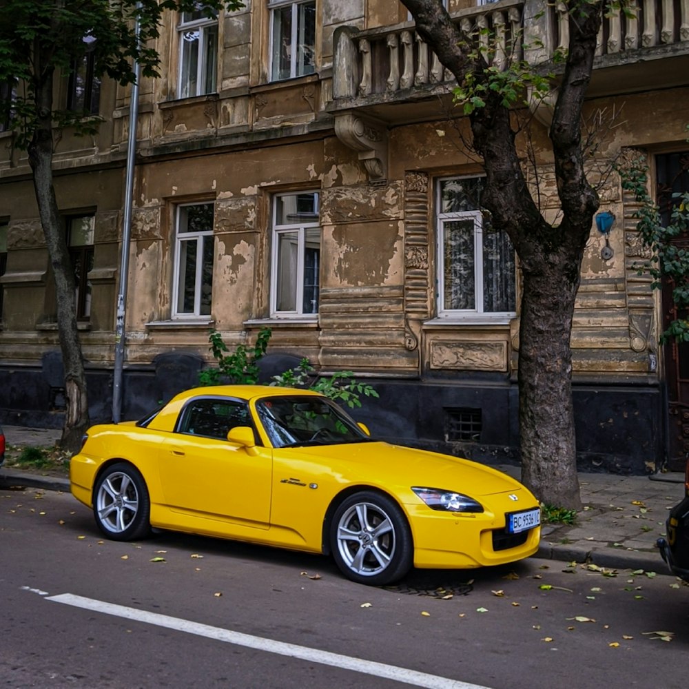 yellow porsche 911 parked beside brown concrete building during daytime