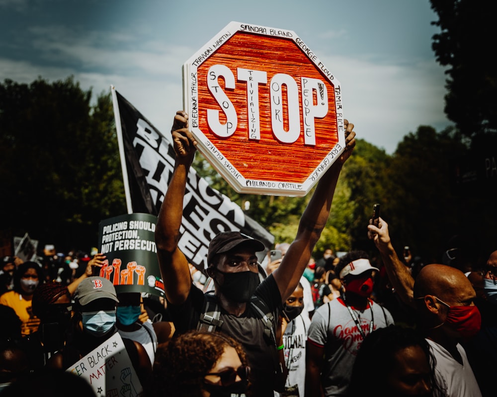 people holding red and white stop sign during daytime