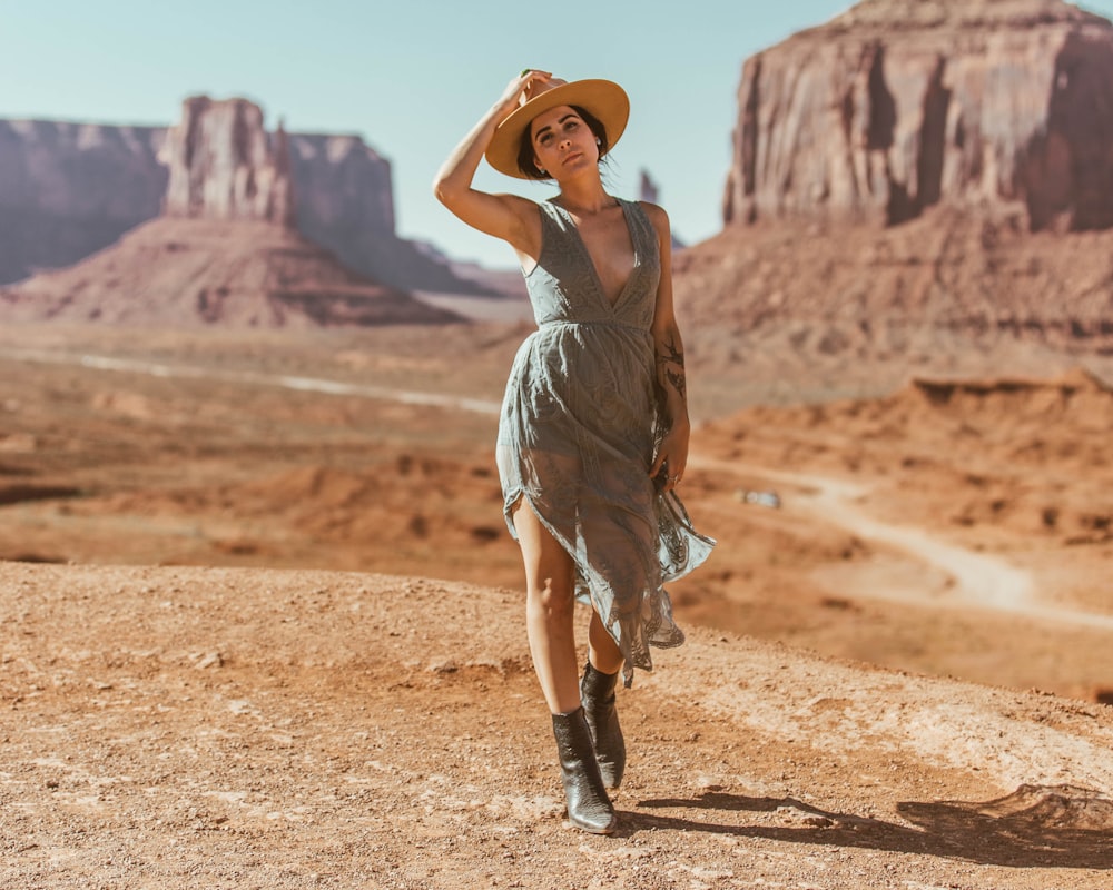 woman in grey dress standing on brown sand during daytime