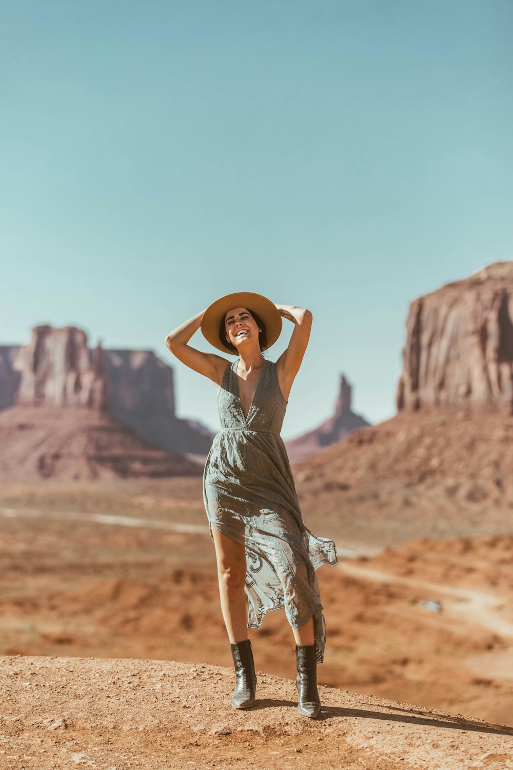 woman in white dress and brown hat standing on brown sand during daytime