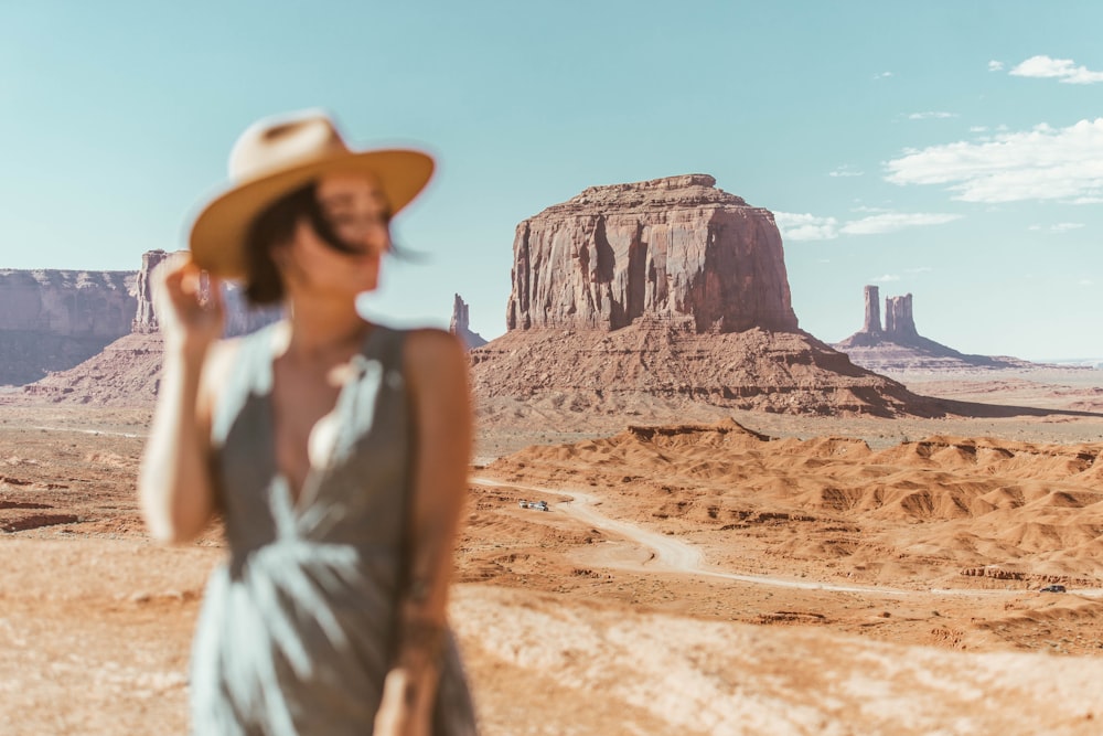 woman in white sleeveless dress wearing brown hat standing on brown sand during daytime