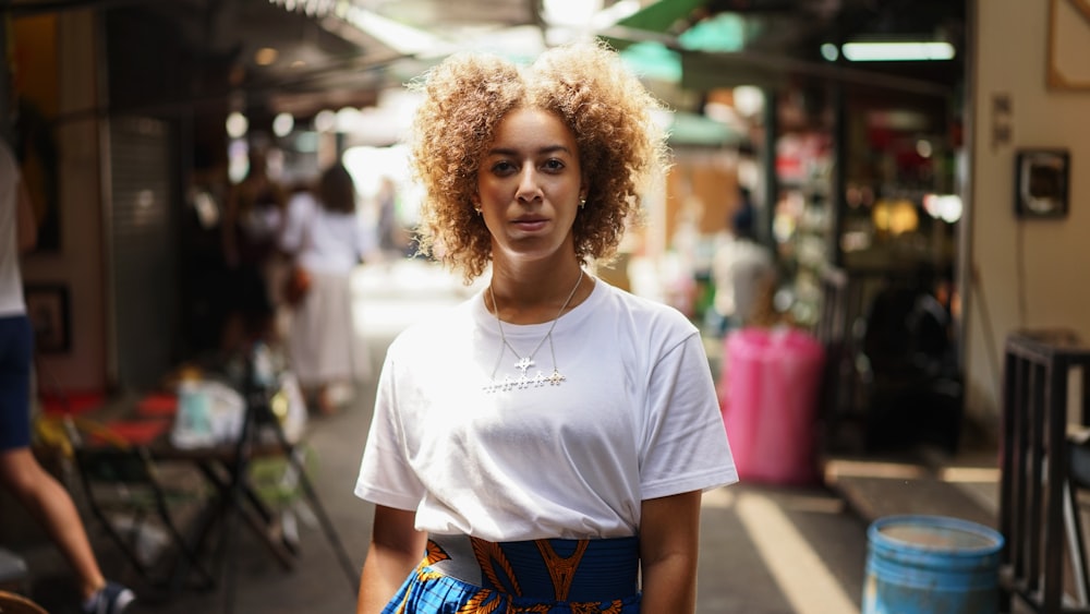 woman in white crew neck t-shirt standing on street during daytime