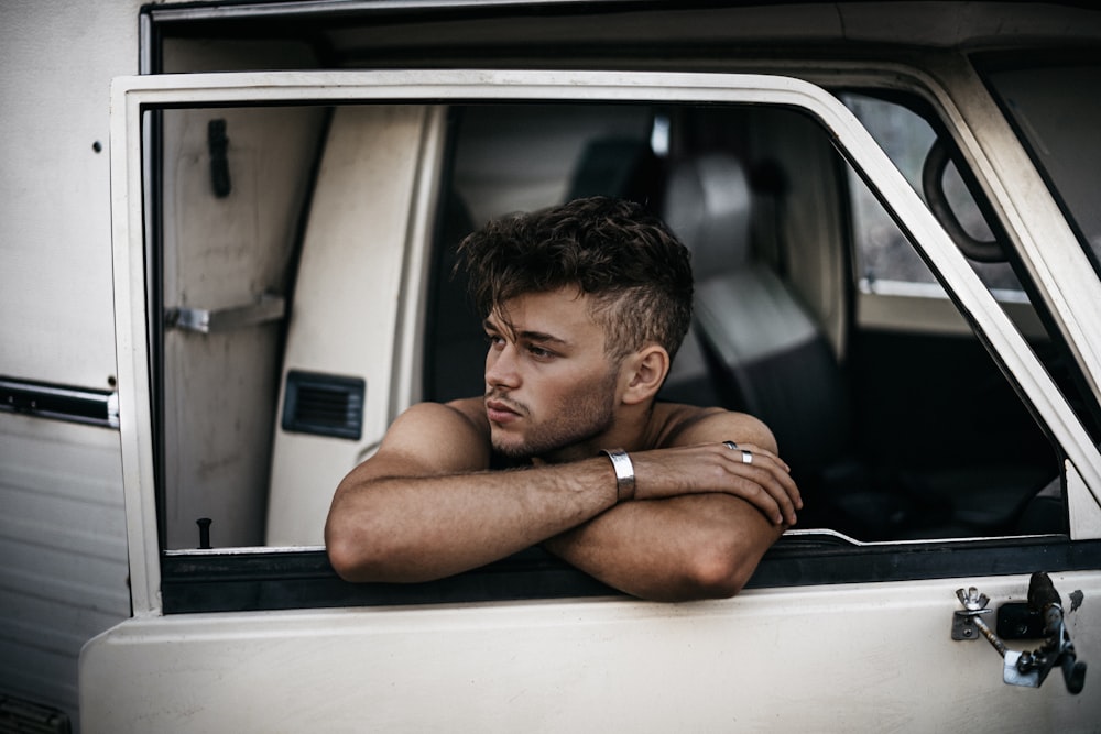 man in black shorts sitting inside car