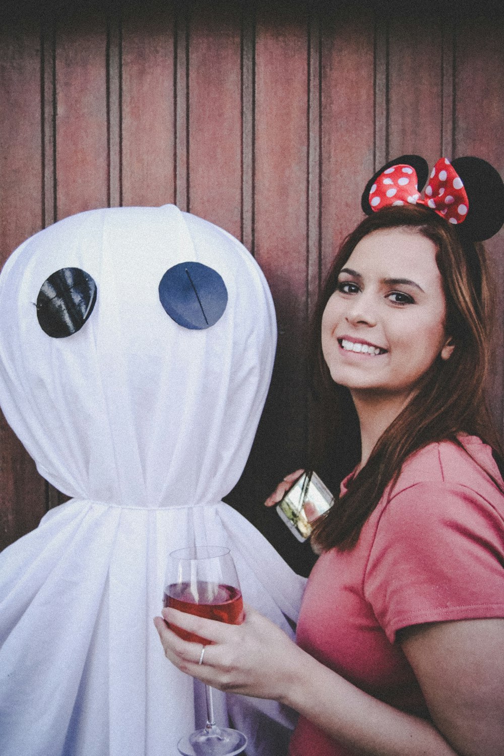 woman in pink long sleeve shirt holding white and black mickey mouse balloon