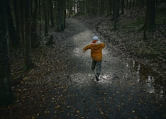 child in brown jacket walking on pathway