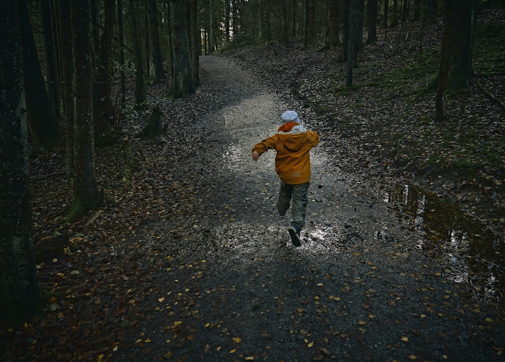 child in brown jacket walking on pathway