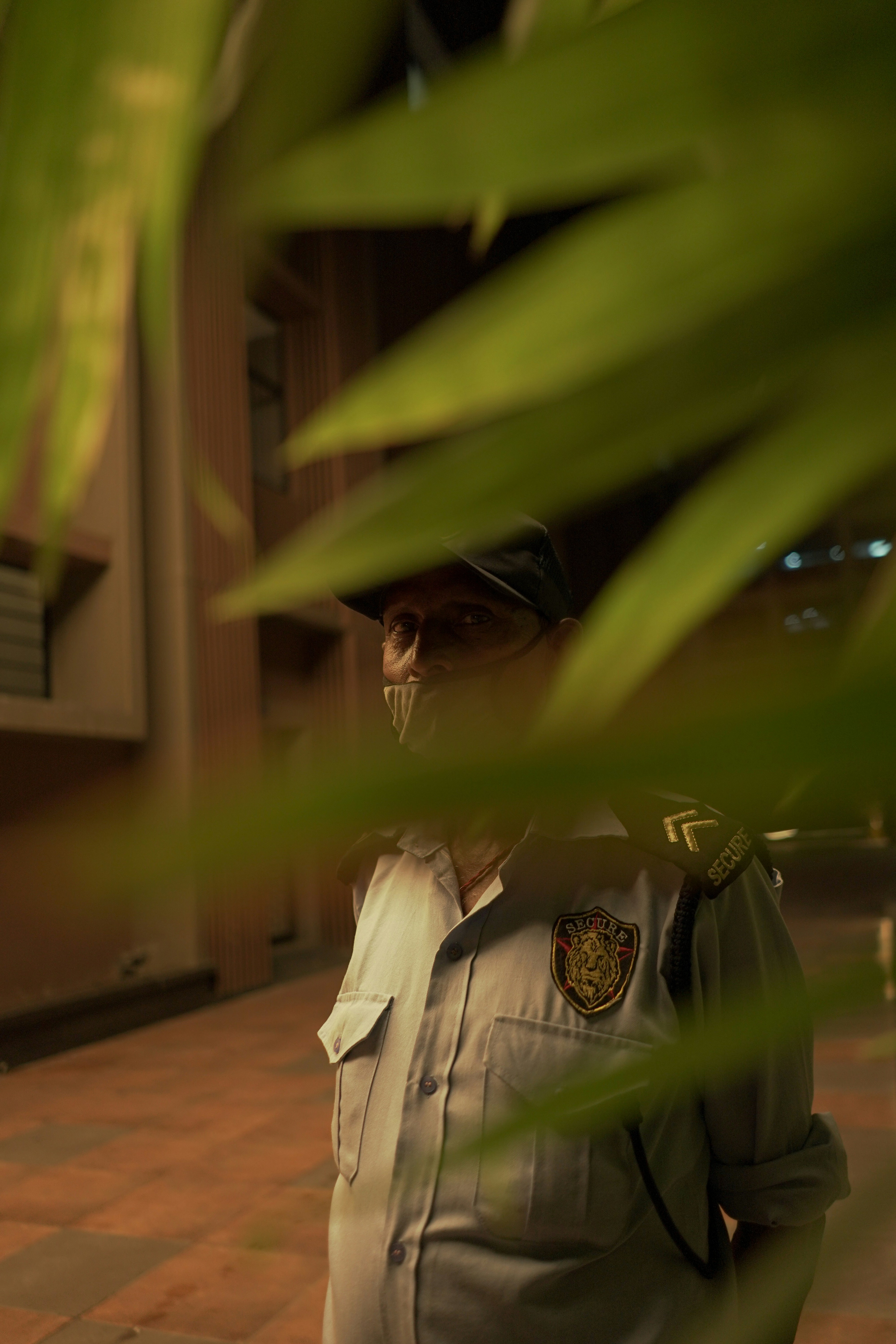 A professional security guard standing alert in front of a modern office building at dusk.