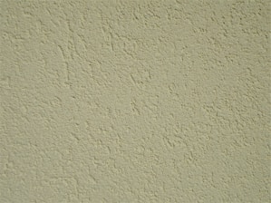 A close-up of a textured wall surface with a rough, uneven finish displaying numerous small bumps and grains.