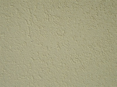 A close-up of a textured wall surface with a rough, uneven finish displaying numerous small bumps and grains.