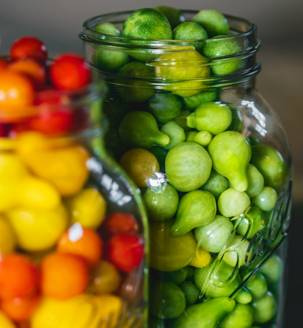 green and yellow round fruits in clear glass jar