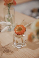 Close-up of a textured stoneware vase in warm orange tones with fresh wildflowers inside.