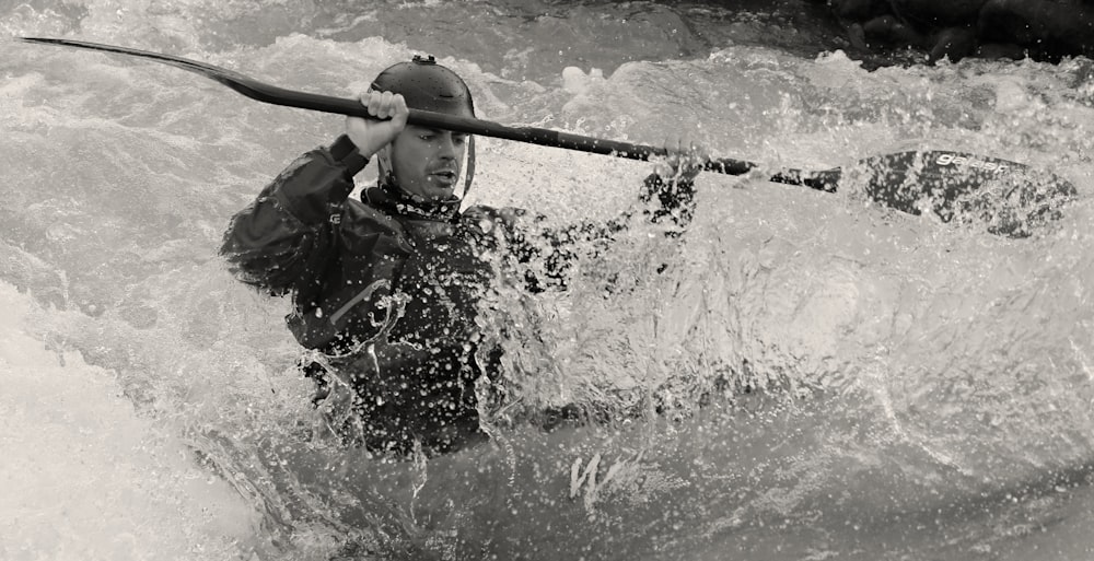 Homme en veste noire tenant un bâton dans l’eau