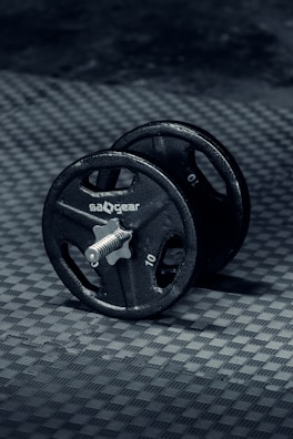 Close-up of a sleek, black dumbbell with textured grip resting on a gym floor.