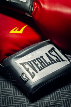 A close-up of a fighter's gloves resting on a training mat.