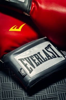 A close-up of colorful boxing gloves resting on a gym floor.