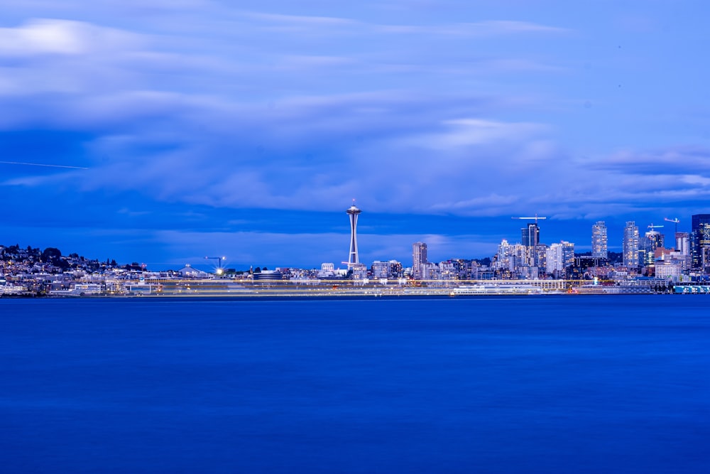 city skyline across blue sea under blue and white sunny cloudy sky during daytime